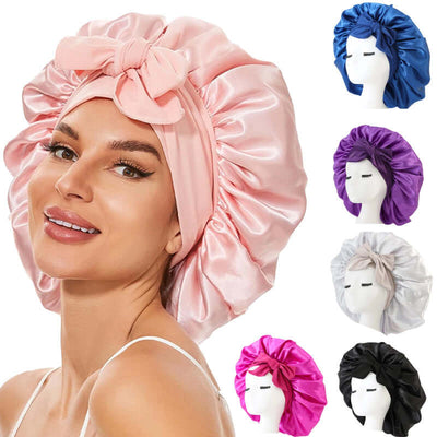Woman wearing a pink satin sleeping bonnet with tie band, surrounded by various colors of sleep caps for hair protection.